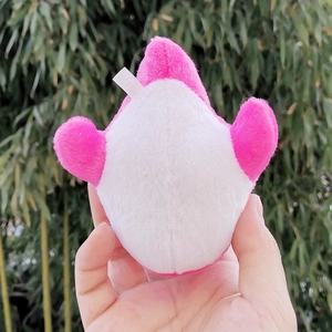 Detailed view of the soft pink and white whale plush toy held in hand outdoors