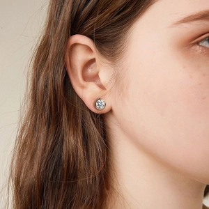 Close-up of bezel-set round zircon stud earring in gold plating on model ear