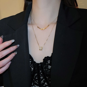 Detail of 18k gold plated double-layer necklace with cubic zirconia cylinder pendant