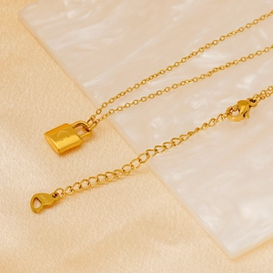 Elegant gold titanium steel padlock necklace on pink silk fabric with marble base