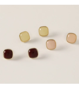 Macro shot of geometric square stud earrings in red, yellow, and pink with gold plating