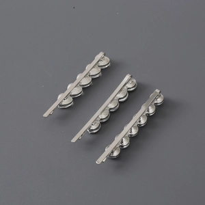 Detailed view of three silver metal hair clips with circular textured wave elements