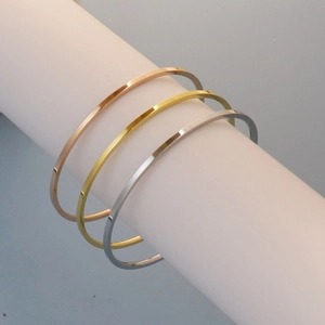 Close-up of three minimalist polished 18K gold-plated stainless steel stackable bangles