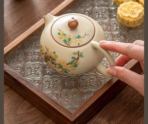 Close-up of a Ru-kiln ceramic teapot featuring yellow flowers and a cute cat illustration