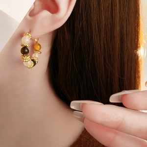 Close-up of a model wearing vintage gold-plated hoop earrings with tiger eye stone beads