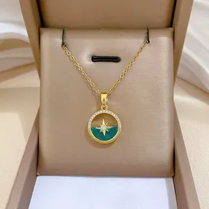 Close-up of gold starburst necklace with green enamel pendant in a luxury gift box
