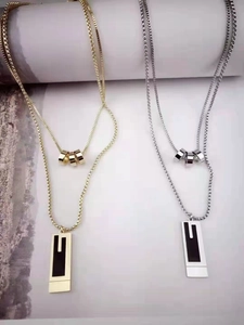 Detailed view of layered titanium steel necklaces with gold and silver rectangular pendants