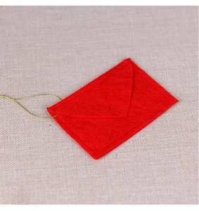 Detailed view of red felt Christmas envelope ornament with gold string on burlap background