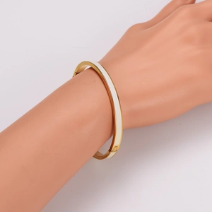 Minimalist gold stainless steel bangle with white enamel inlay on a mannequin hand
