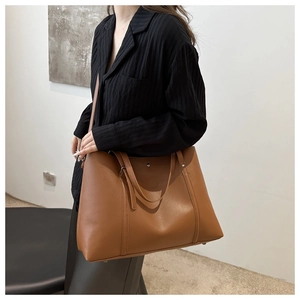 Brown large-capacity PU leather tote bag with dual handles shown on model's shoulder