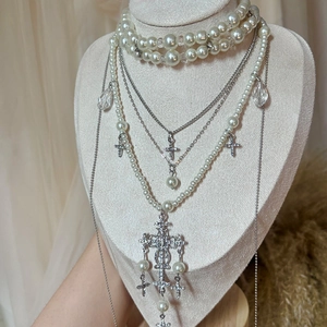 Elegant multi-layer baroque pearl necklace with rhinestone cross pendants on a display stand