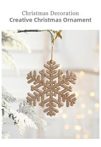 Detail of a sparkling golden glitter snowflake ornament hanging on a snowy Christmas tree branch