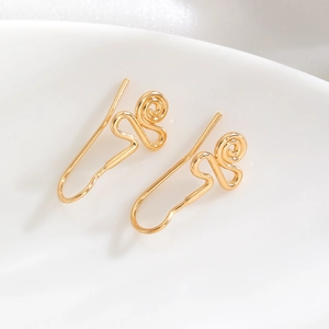 Close-up of golden spiral geometric hoop earrings in a minimalist abstract metal design