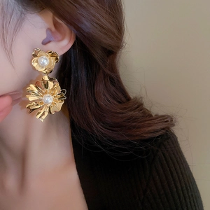Gros plan de boucles d'oreilles fleurs dorées avec perles blanches sur un mannequin