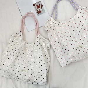 Dettaglio di borse tote in tela con motivi a cuore e manici colorati in corda intrecciata