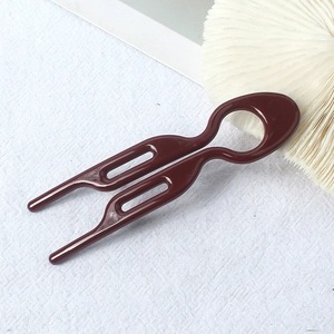Detail view of the sleek deep brown U-shaped hair fork pin for elegant bun styling
