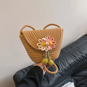 Handmade woven straw bucket bag with floral crochet decorations and shoulder strap