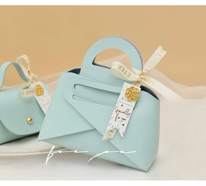 Detail of light blue faux leather wedding favor bag with gold flower charm and ribbon