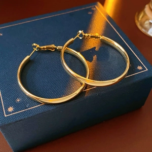 Detail view of large gold hoop earrings on luxury dark blue starry gift box with warm lighting