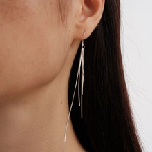 Dettaglio orecchini a nappa in argento su modella con eleganti frange metalliche lunghe