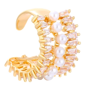 Macro detail of gold ear cuff featuring embedded pearls and baguette-cut zircons