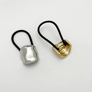 Detail view of gold textured and silver polished metal cuff elastic hair ties for ponytails
