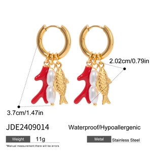 Detail view of gold hoop earrings featuring red coral charms and white baroque pearls