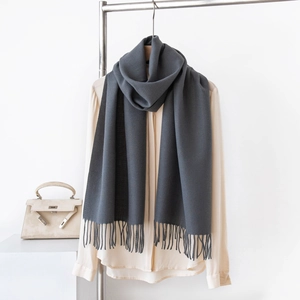Dettaglio della sciarpa grigio scuro effetto cashmere con frange su camicia beige