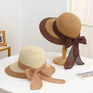 Detailed view of straw sun hats with large bows and bicolored textures for summer beach