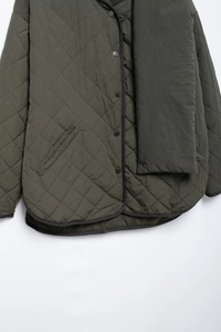 Detail of dark green quilted jacket featuring diamond stitching and matching scarf