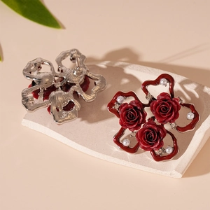 Vintage red rose stud earrings with pearls and crystals on a stone display plate