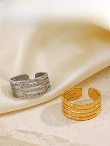 Detailed view of layered 18K gold and silver steel rings with hammered texture on satin