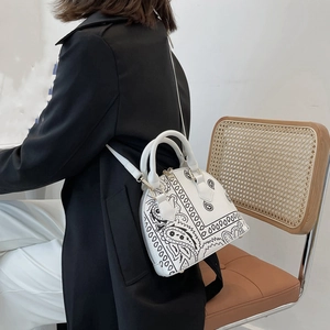 Close-up of white paisley shell bag with gold zippers worn by a model on a crossbody strap