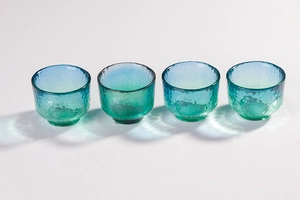Detail of four peacock blue hammer-textured gradient glass sake cups on white background