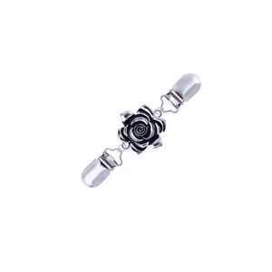Détail d'un clip de cardigan vintage argenté avec rose noire et petite chaînette