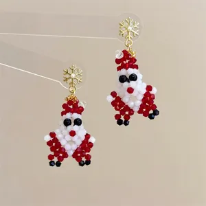 Close-up of handmade beaded Santa Claus earrings with golden snowflake hooks