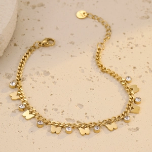 Elegant gold butterfly bracelet with zircon crystals on beige stone background