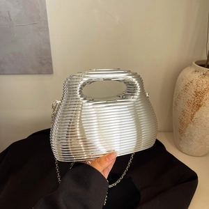 Silver metallic ribbed evening clutch bag with chain strap held against a black blazer