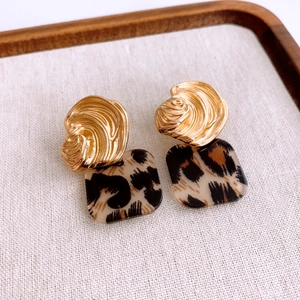 Detailed macro view of resin leopard print square earrings with golden textured metal tops