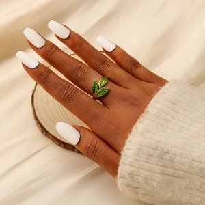 Detail of leaf-shaped ring in antique gold and emerald green enamel on a model hand