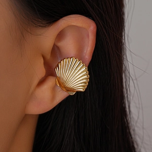 Detailed macro view of golden shell ear cuff featuring polished radial textures on the ear
