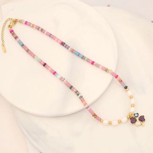 Detail of colorful beaded necklace with purple clover pendant and pearl accents
