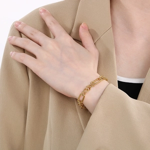 Detail of twisted gold chain bracelet styled on a beige blazer for a high-end look