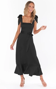 Detail of elegant black dress showing bow shoulder straps and tie waist on white background