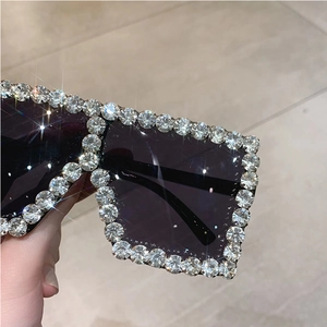 Close-up of oversized square sunglasses with hand-set sparkling silver rhinestones and black lenses