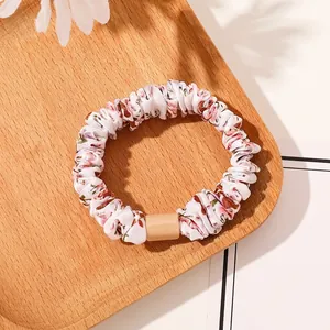 Detail of floral printed scrunchie with pink flowers on a rustic wooden tray
