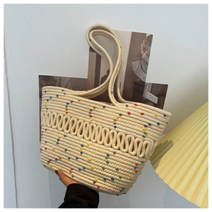 Detail of hand-held beige woven tote bag with colorful dots for summer beach vacations