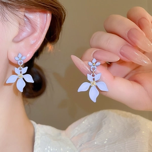 Detail of purple floral earrings with gold accents shown on model and in close-up