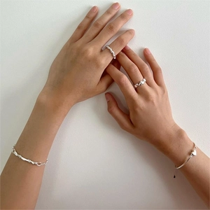 Detail of silver twisted chain bracelets and heart motif rings worn by a model