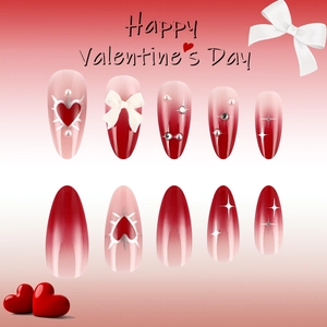 Detailed view of red almond press-on nails with 3D bows, pearls and heart charms